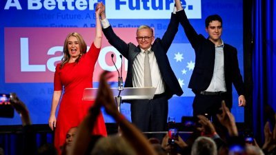 在澳洲工党位于悉尼的总部，阿尔巴尼斯（中）与伴侣和儿子在台上接受支持者的欢呼。（图取自路透社）