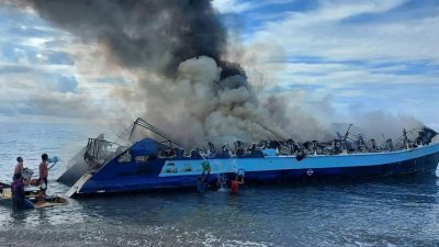 菲律宾一艘在奎松省雷亚尔镇港口附近的渡轮起火，冒出浓烟，人们用水桶从海上盛水扑灭大火。（图取自菲律宾海岸警卫队/法新社）