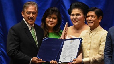 小马科斯（右）周三在奎松市的众议院，从参议院议长索托手中接过当选证书，其曾是菲律宾第一夫人的母亲伊美黛，以及目前是一名参议院的姐姐艾米陪同。（图取自法新社）