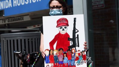 美国全国步枪协会（NRA） 周五在得克萨斯州休斯敦举行年会，民众举著画报在会场外抗议。（图取自路透社）