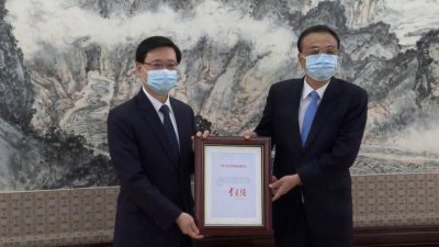 中国总理李克强（右）向李家超颁《国务院令》，任命李家超为香港第6任特首。（图取自香港电台）