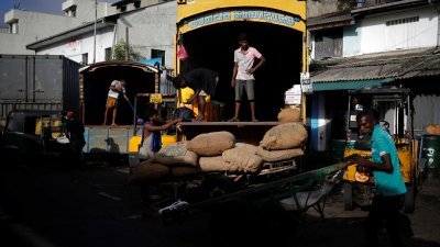 在斯里兰卡首都科伦坡的一个批发市场，工人从罗里卸下袋装米。（图取自路透社）