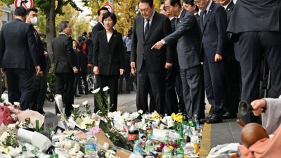 韩国总统尹锡悦（中）与韩国总理韩悳洙（中右）于周二上午，前往踩踏事故现场附近的首尔地铁6号线梨泰院站1号出口前设置的的临时纪念处。（图取自法新社）