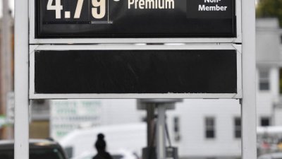 在美国宾夕法尼亚州一处加油站，一名妇女10月19日在在标有汽油价格的告示牌下加油。（图取自路透社）