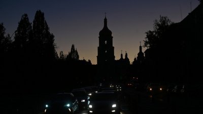 乌克兰首都基辅部分电力基础设施瘫痪，城市陷入近乎黑暗中，车辆周一沿著街道行驶，背景是圣索菲亚大教堂。（图取自法新社）