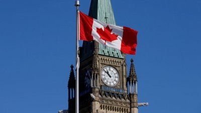 在加拿大安大略省渥太华的国会山和平塔前飘扬的加拿大国旗。（图取自路透社档案照）