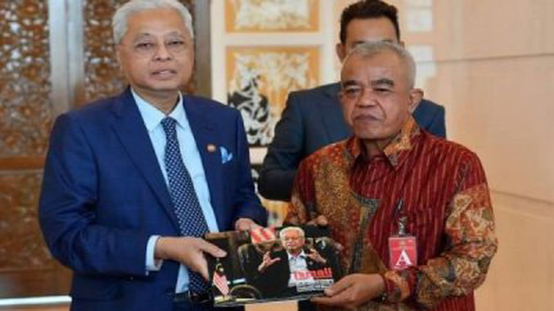 看守首相依斯迈沙比里（左）赠送题为《依斯迈沙比里安全引领导：克服新冠危胁》桌边书予印尼记者协会（ISWAMI）主席的卡玛罗康。