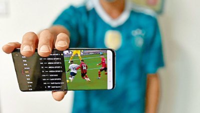 有购买了电视APP的青年展示手机画面，当中有不少可观看足球赛事和世界杯的外国电视频道。（图取自香港《星岛日报》）