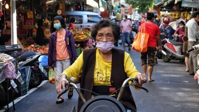台湾新冠疫情持续，在台北，市民配戴口罩前往大稻埕太平市场采买食材，防疫不松懈。（图取自中央社）
