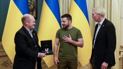 民主党参议员库恩斯（左）和共和党参议员波特曼（右）上周四造访乌克兰首都基辅，并将美国宪法中心在周二颁给乌克兰总统泽连斯基的“自由勋章”展示给对方。（图取自推特/Senator Chris Coons）