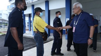 韩沙再努丁（右）与一名准备提前投票的便衣警察握手问候。