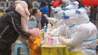 今年1月5日在中国河南省郑州，身著防护服的医务人员在全市范围内对新冠肺炎病例进行核酸检测时，从居民身上采集拭子。（图取自中新社/路透社档案照）