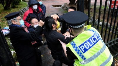 10月16日位于中国驻曼彻斯特总领事馆，英国警方试图将被打的港人示威者Bob Chan（戴黄色口罩者）从领事馆范围内拉出来。（图取自The Chaser News/法新社档案照）