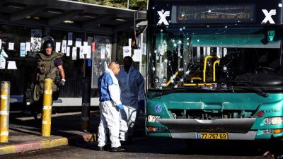 耶路撒冷周三发生2宗车站爆炸事件，炸弹专家和警员事后在其中一个公交车站，检查一辆受损的巴士。（图取自路透社）