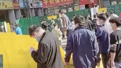 路透社截取周三社交平台上的影音画面显示，在中国河南省郑州富士康厂区爆发抗议活动后，一群人穿过倒塌的围栏。