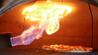  在德国波恩一家餐厅，传统意大利比萨烤箱中用天然气烤制的比萨。（图取自路透社档案照）