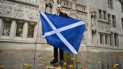 在英国最高法院阻止苏格兰自行举办独立公投后，一名苏格兰独立支持者在位于伦敦的最高法院外展示一面苏格兰旗。（图取自法新社）