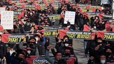 韩国运输重镇义王市内，数以百计货车司机周四在大批警员戒备下，高举“联合对抗”标语及大叫“我们停手，世界停转”等口号游行。（图取自韩联社/路透社）