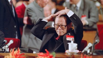 1992年10月12日，时任中共中央总书记的江泽民在北京中共十四大上发表讲话前，用梳子整理头发。（法新社档案照）