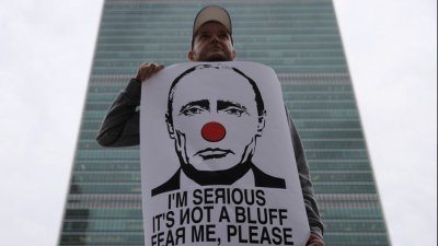 一名男子当地时间周五在美国纽约联合国总部外，手持海报抗议俄罗斯总统普京。（图取自路透社）