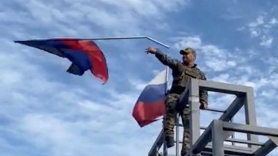 社交媒体视频截图显示，一名乌军将悬挂在利曼一座纪念碑上的顿涅茨克共和国国旗拿下后往下丢。（图取自Oleksiy Biloshytskyi/路透社）