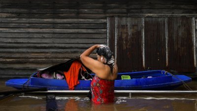泰国曼谷郊区暖武里府的Tha-it清真寺附近强降雨后，一名妇女周二在被洪水淹没的道路上洗澡。（图取自路透社）