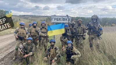 在卢甘斯克地区内的赫雷基夫卡村（Hrekivka），一个乌克兰部队或跪或站在路标周围，同时还展示乌克兰国旗。（图取自CNN）