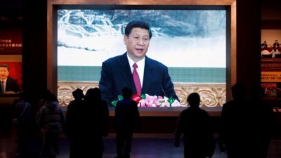 在北京的中国共产党历史展览馆，参观者经过展示中国国家主席习近平的巨型屏幕。（图取自路透社）