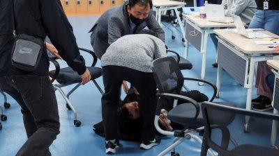 在韩国首尔的一个社区服务中心，其中一名遇难者的父母无法接受孩子身亡的消息，情绪激动的跌躺在地，周围的人赶紧上前准备扶起对方。（图取自路透社）