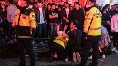 上周六在韩国首尔梨泰院踩踏事故现场，警员在路旁协助伤者。（图取自法新社）