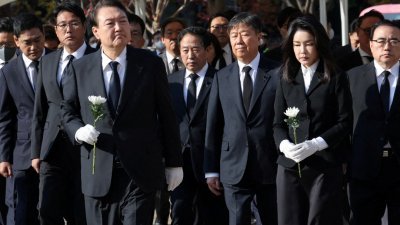 韩国总统尹锡悦和夫人手持白花，前往设在首尔广场首尔图书馆正门前的集体焚香所，献花悼念遇难者。（图取自韩联社/路透社）