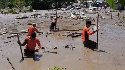 上周日在马京达瑙省达图奥丁辛苏特镇，救援人员在进行搜索幸存者时，使用杆子插入泥堆中。（图取自菲律宾海岸警卫队/法新社）