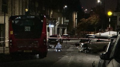 伦敦警方封锁事发地区的道路，并在现场调查一辆严重受损的汽车。（图取自推特@VinnyMcAv）