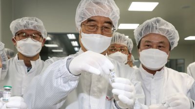 图为韩国总理韩德洙（中）周五至药厂检视SKYCovione疫苗。（图取自台湾中央社/韩联社）