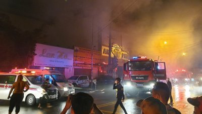 越南平阳省一家卡拉OK酒吧，周二晚发生大火，滚滚浓烟不断冒出，赶到现场的消防人员在现场展开救援。（图取自越南通讯社/法新社）