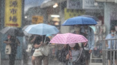 风暴“梅花”增强为强台风，预料将横过台湾以东海域。图为周日台北地区下起雨来，民众走在公馆商圈撑伞避雨。（图取自中央社）