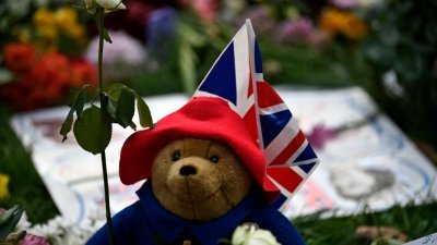 在伦敦白金汉宫附近的格林公园，一只帕丁顿熊泰迪熊与花卉向女王致敬。（图取自法新社）
