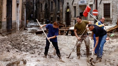 意大利中部马尔凯地区下暴雨导致洪灾，居民在积水退去后用铲子清理泥泞的街道。（图取自路透社）