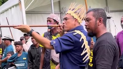 阿末费沙（右2）在原住民村运动会上，试用打猎喷筒射靶心。