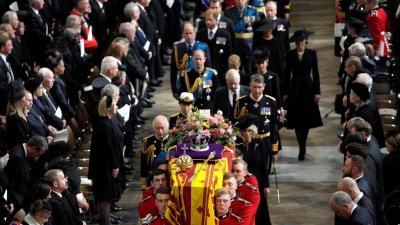 西敏寺的国葬仪式结束后，卫兵抬起女王灵柩，准备放置在火炮车架上送往温莎城堡。国王查尔斯三世、王后卡米拉等一众王室成员跟随在棺木之后。（图取自路透社）