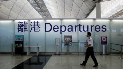 一名机场保安走过香港机场出发大厅的标志。（路透社档案照）