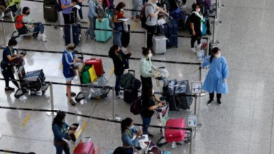 旅客在香港国际机场排队，等候搭乘巴士前往检疫酒店隔离。（图取自路透社）
