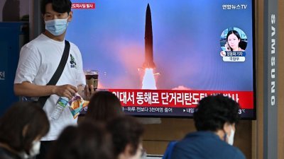 朝鲜周日清晨发射了一枚疑似弹道导弹， 韩国民众在首尔火车站观看相关的新闻报导。（图取自法新社）