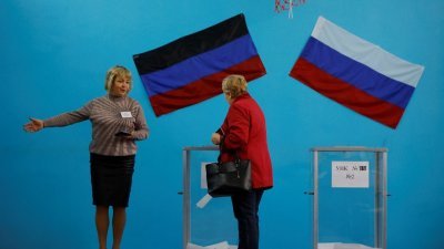 周二，在顿涅茨克州，一名选举委员会成员在投票站为选民指路。（图取自路透社）