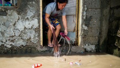 台风奥鹿在菲律宾引起大范围水灾，目前正往泰国和越南方向前进。在菲律宾布拉干省，洪灾后一名妇女正在清理住宅。（图取自路透社）