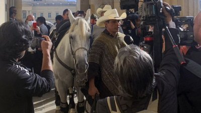 哥伦比亚参议员巴雷拉牵著马走上国会大楼的阶梯，并接受媒体访问。（图取自法新社）