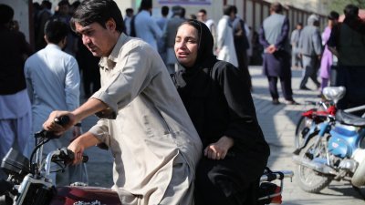 阿富汗喀布尔教育中心袭击发生后，一名女性乘坐著摩托车抵达医院寻找亲属。（图取自法新社）