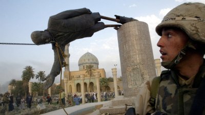 2003年4月9日在伊拉克首都巴格达市中心，一名美国士兵看著当时伊拉克总统萨达姆的巨型雕像被拉倒。（图取自路透社档案照）