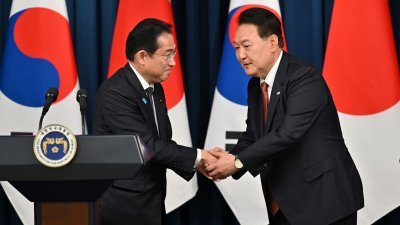 日本首相岸田文雄（左）本月7日访问首尔，在与韩国总统尹锡悦的联合记者会上握手。（图取自路透社）