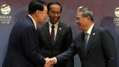 9月6日在印尼雅加达举行的东盟+3峰会上， 韩国总统尹锡悦（左）与中国总理李强握手，中间为印尼总统佐科。（图取自路透社）